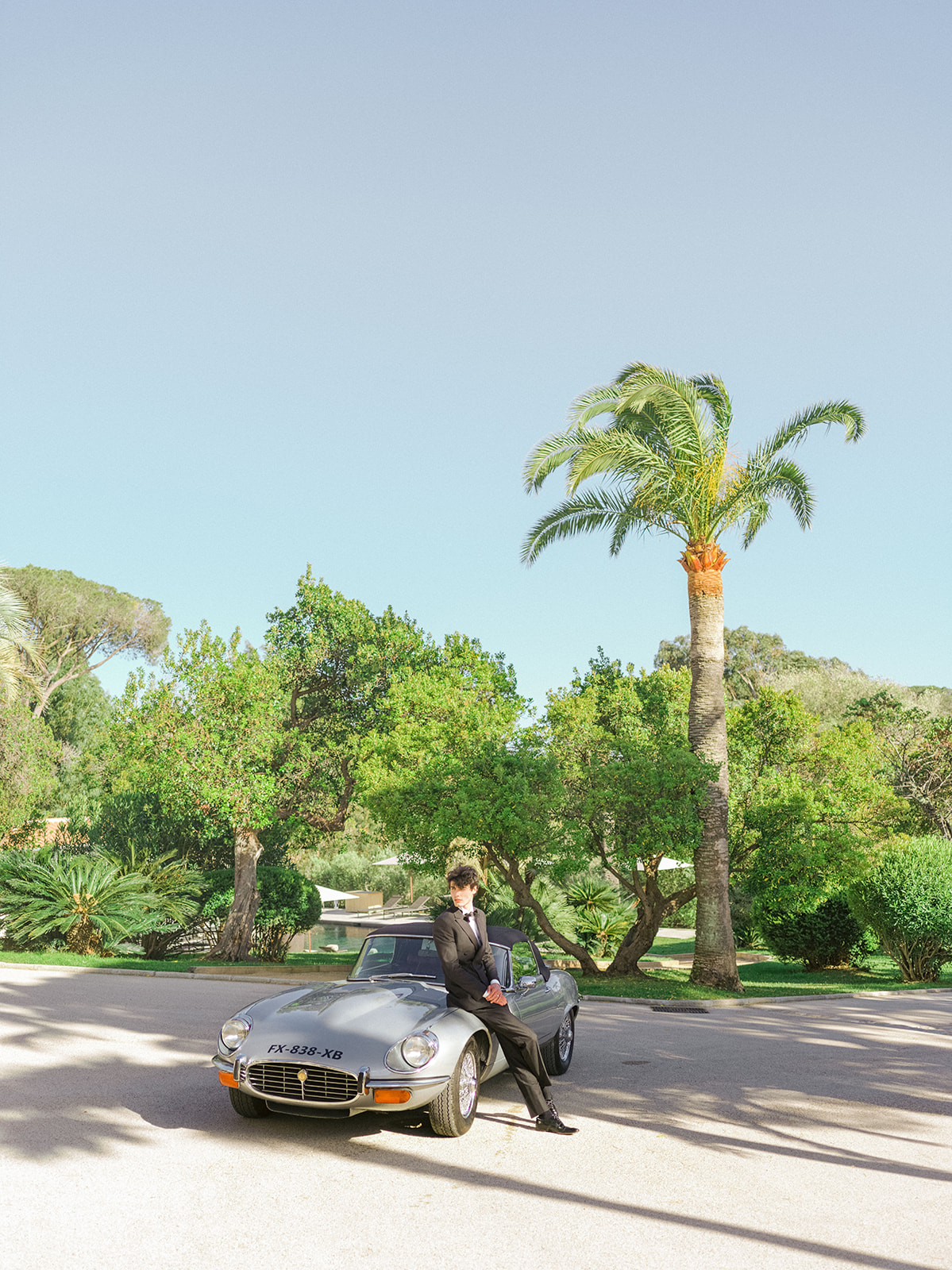 Groom with a classic Jaguar beneath palm trees near Saint-Tropez